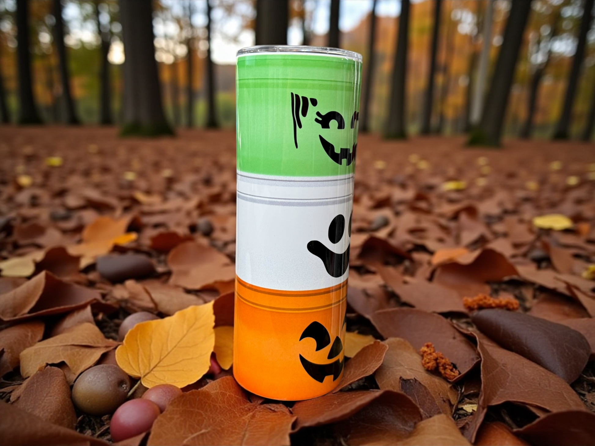 tumbler that looks like a Stack of Halloween-themed cups on a bed of autumn leaves with a forest background
