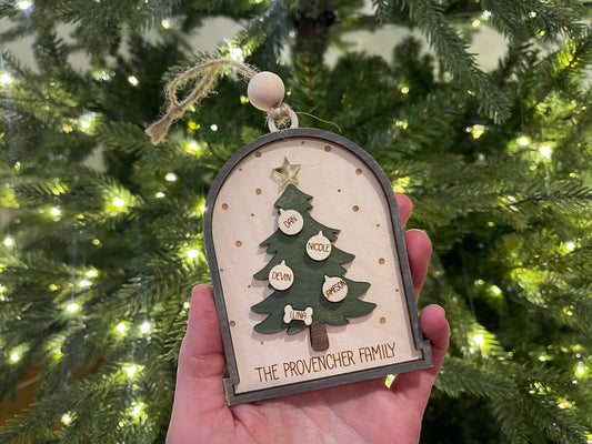 Wooden arch ornament with green christmas tree cut out with ornaments with peoples names and a golf tree with twine rope to hang by