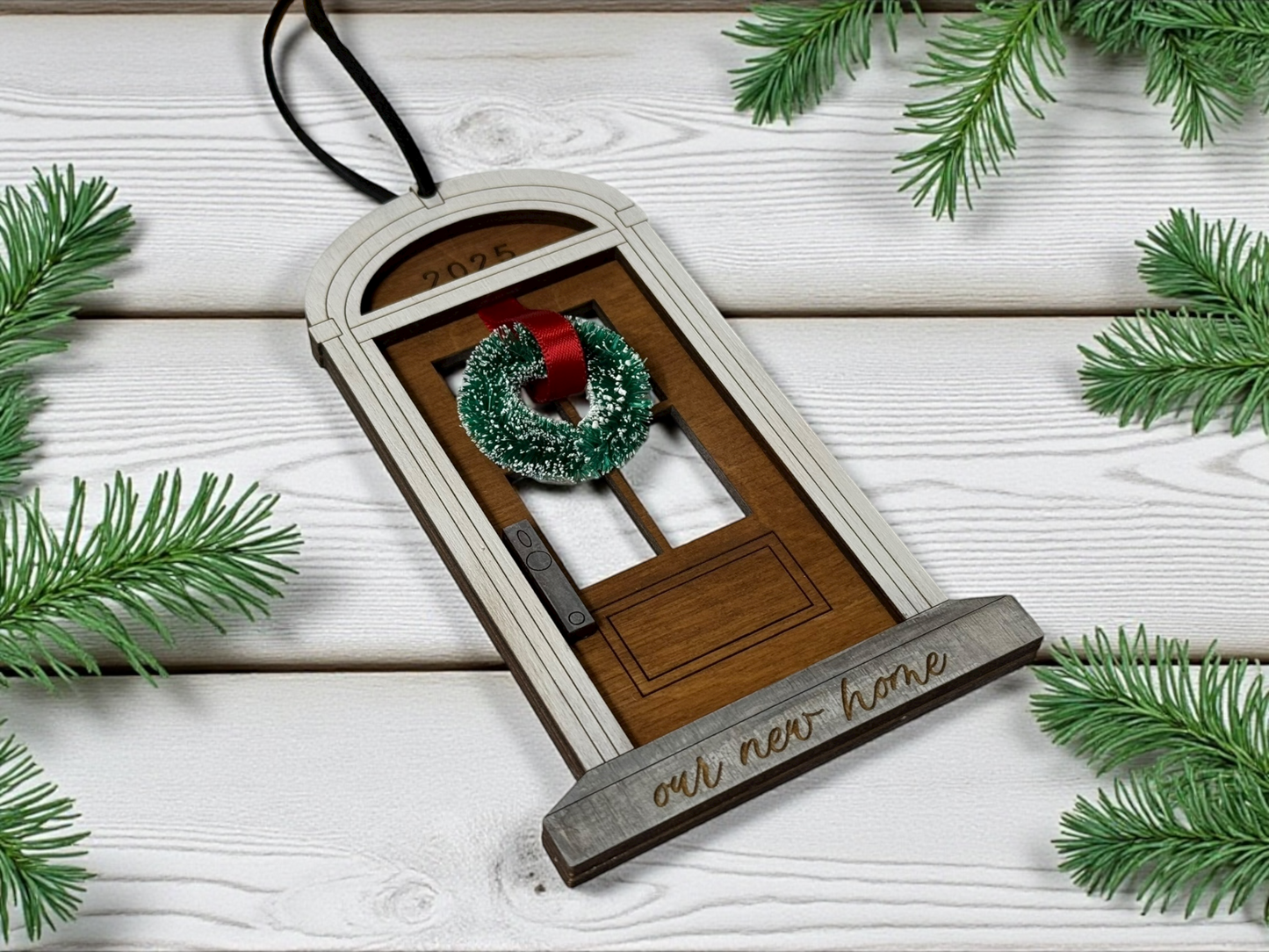 Decorative door ornament with a wreath on a wooden surface with pine branches.