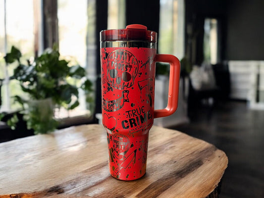 Red 40oz tumbler with handle on a table, with drawings to deal with true crime on the cup. 