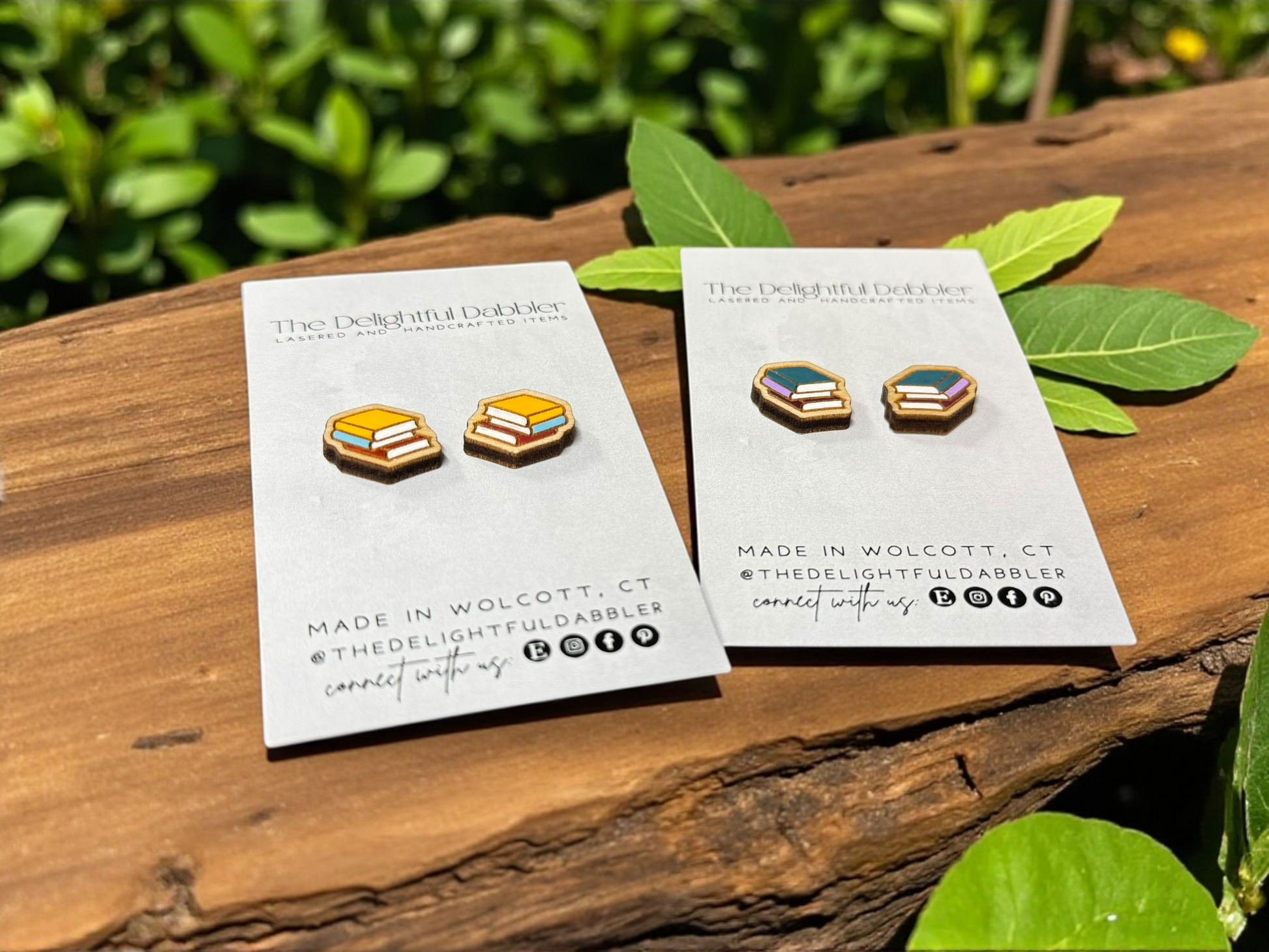 twos Pairs of handpainted wood earrings on a card with 'The Delightful Dabbler' branding, placed on a wooden surface with leaves in the background